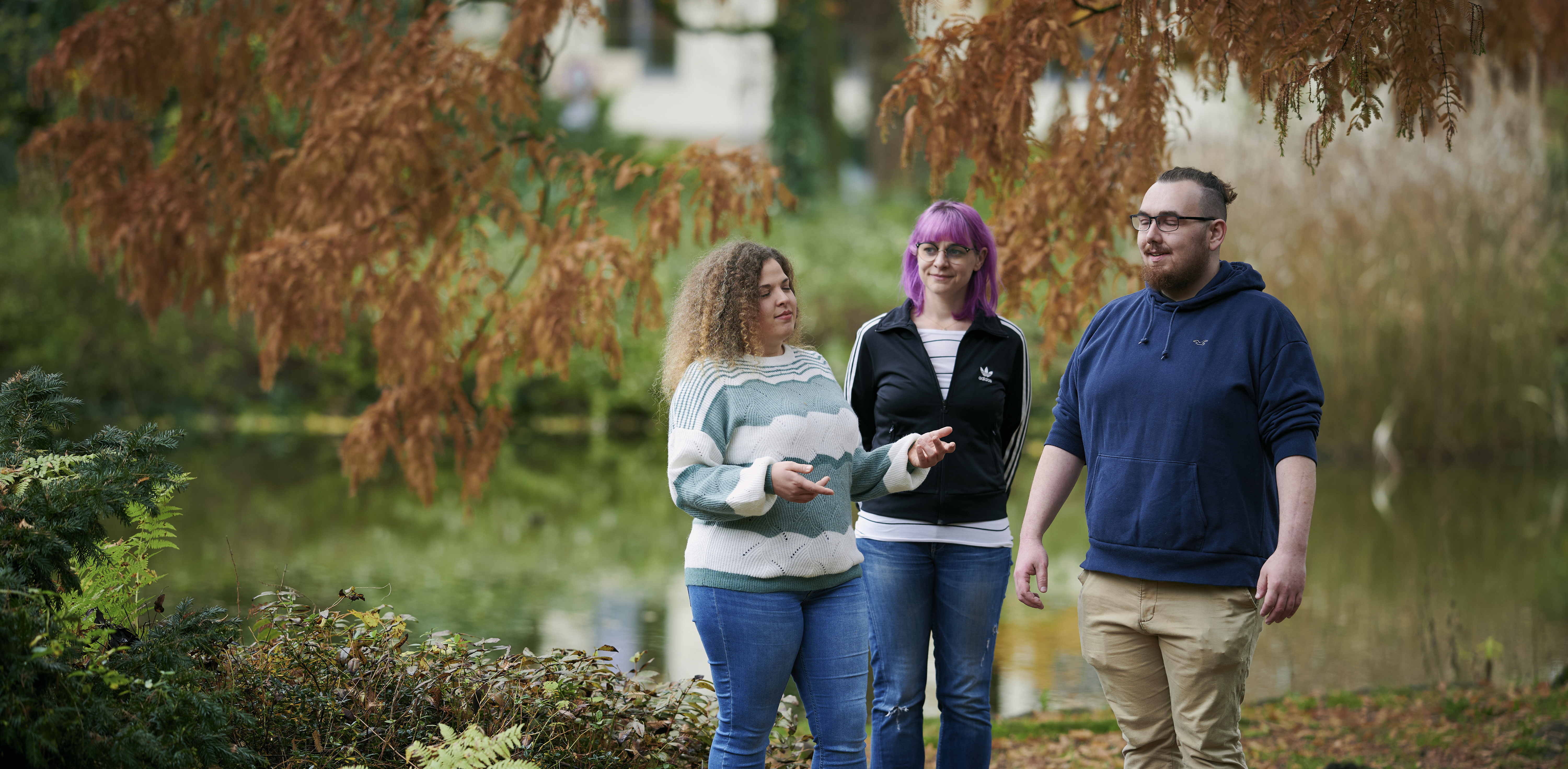 Drei Menschen stehen in der Natur und machen Atemübungen