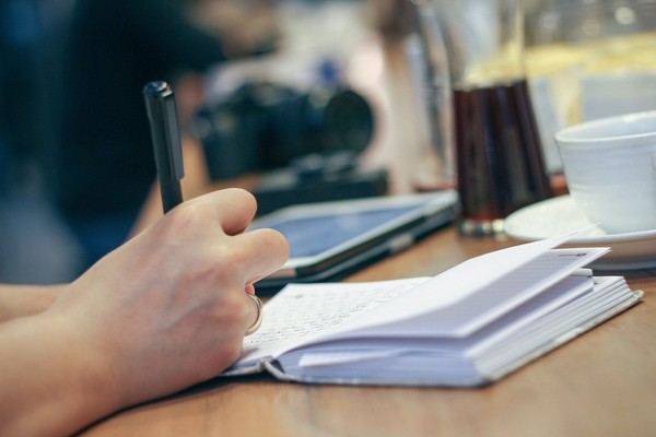 Person schreibt in Notizbuch