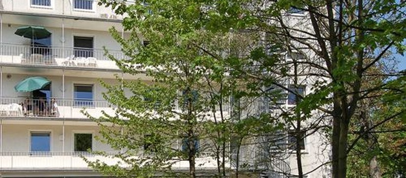 Gebäude mit mehreren Stockwerken und einem Baum im Vordergrund
