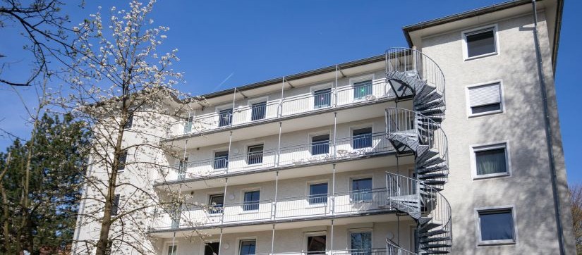 Gebäude mit mehreren Stockwerken und einem Baum im Vordergrund