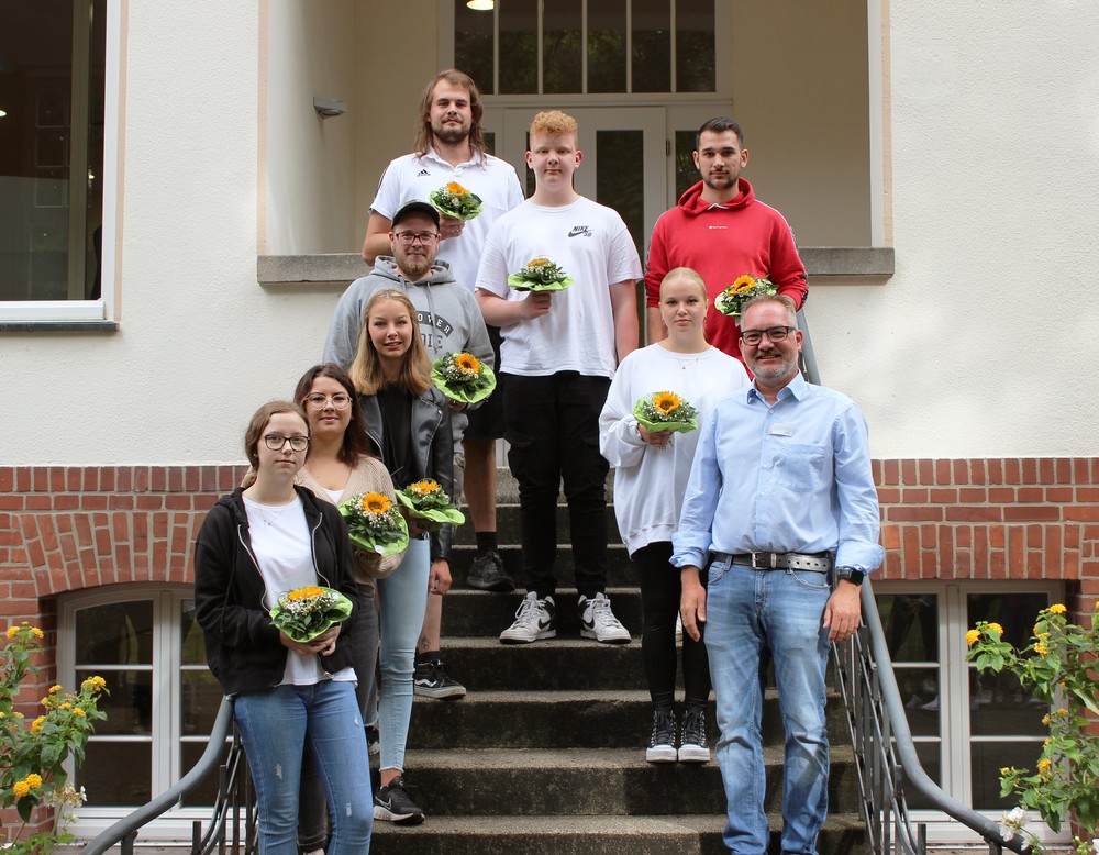 Junge Menschen stehen auf einer Treppe und gucken in die Kamera.